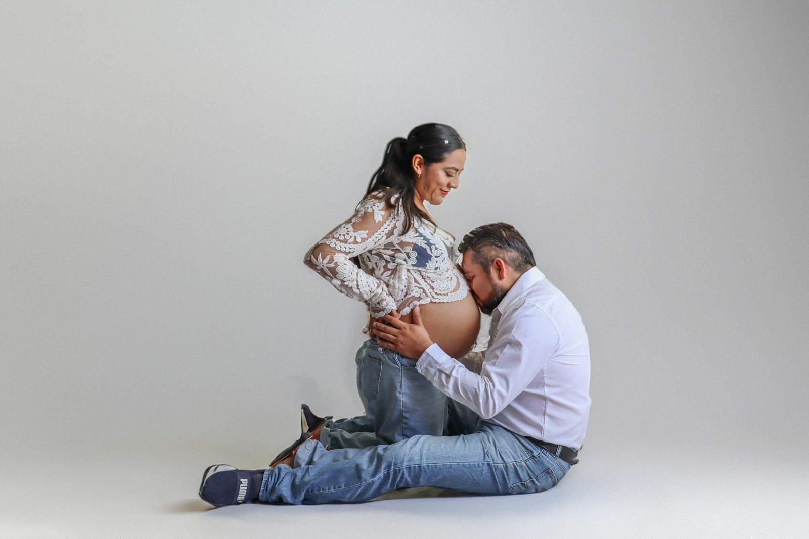 a man kneeling down next to a pregnant woman